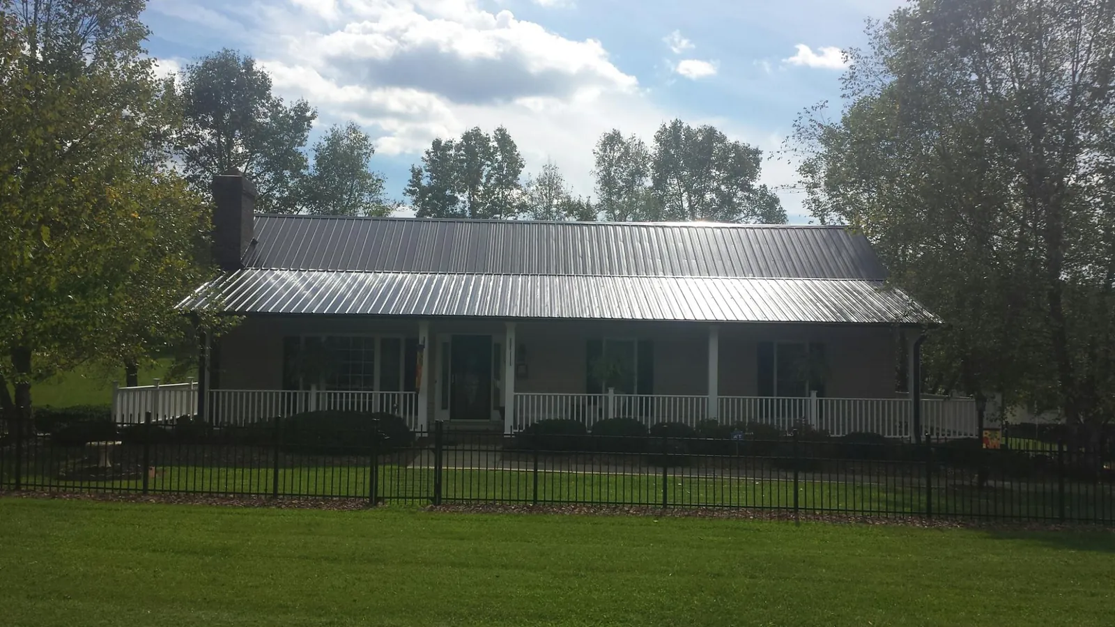Gray metal roof on a brick ranch with a full width front porch — Gutter Guard Installation work by our crew in Spring Grove